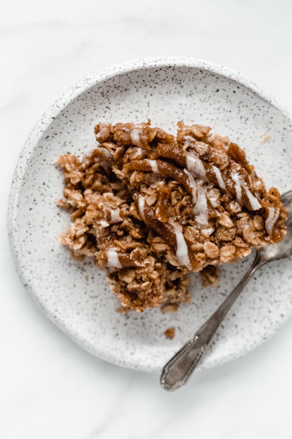 a slice of cinnamon roll baked oatmeal on a small white speckled plate