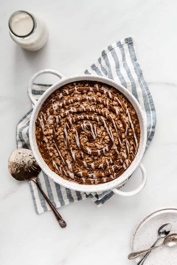 baked oatmeal in a round baking dish on a striped blue napkin topped with cinnamon sugar swirl