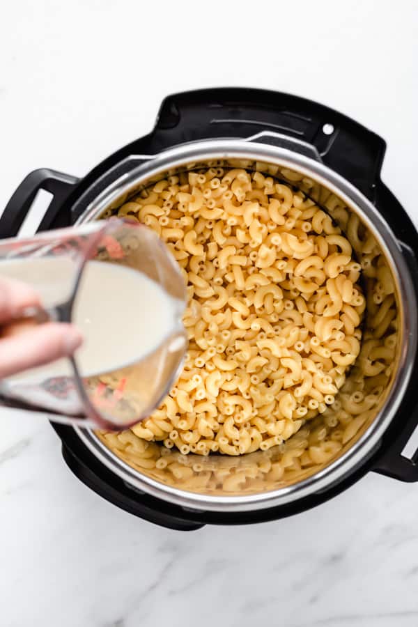 mac and cheese in an instant pot with milk being poured in it