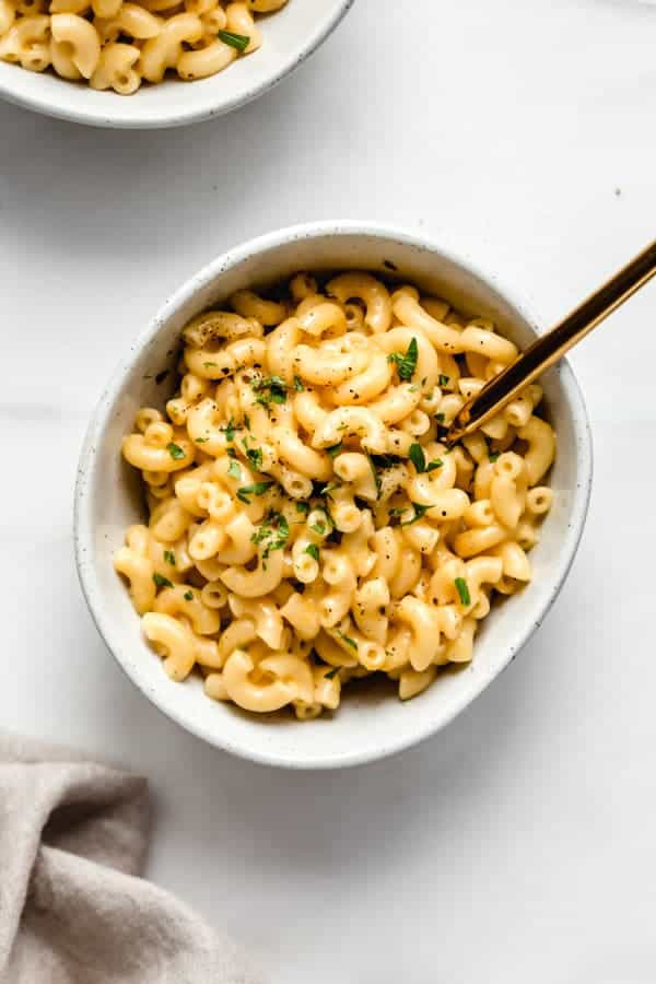 a bowl of mac and cheese with a gold fork in it