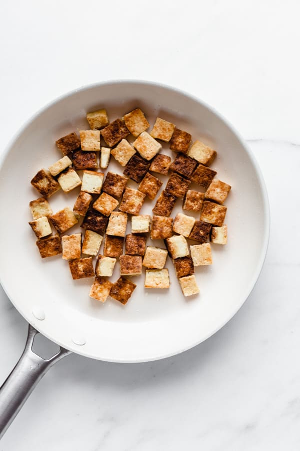 a white pan with cubes of cooked tofu in it
