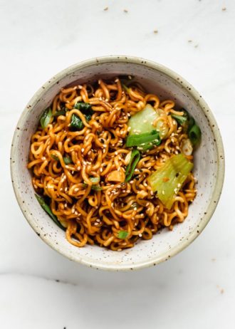 Ramen noodle stir fry in a blue ceramic bowl topped with sesame seeds