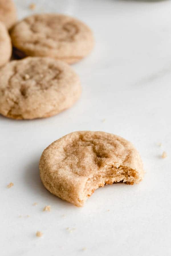 a snickerdoodle cookie on a marble board with a bite taken out of it