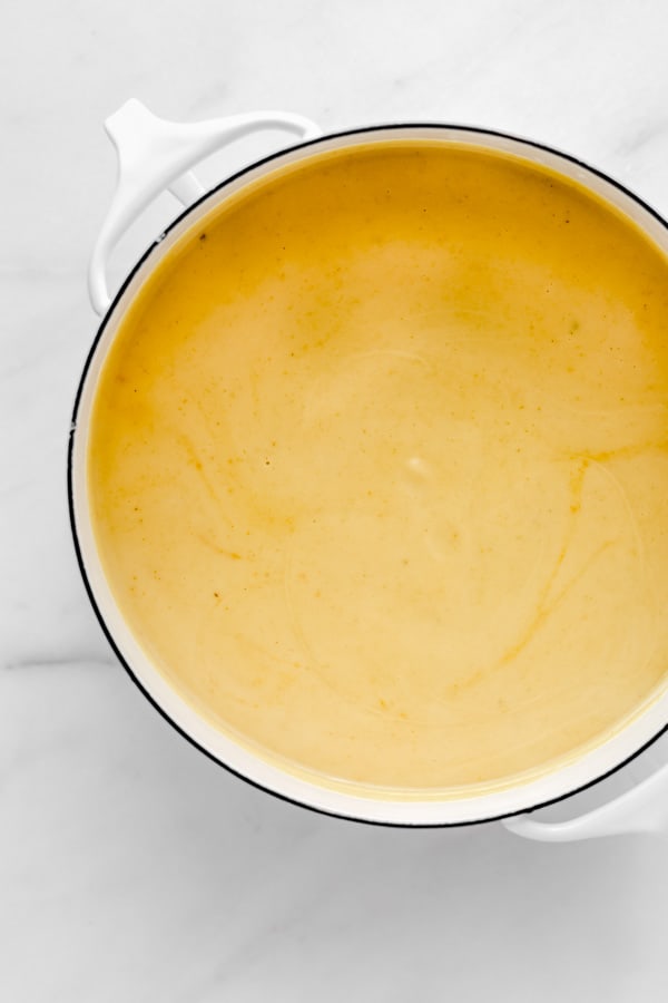 a top down view of yellow curried cauliflower soup in a white pot