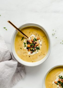 a bowl of curried coconut cauliflower soup with a gold spoon in it