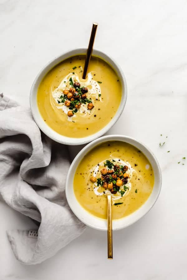 two bowls of curried coconut cauliflower soup topped with roasted chickpeas