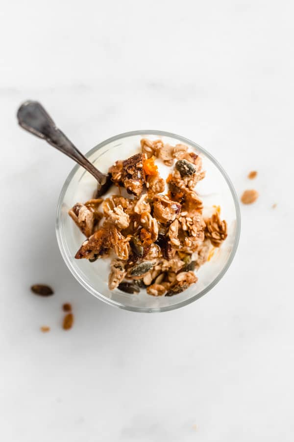 a top down view of a cup of yogurt topped with orange cardamom tahini granola