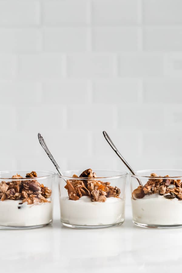 three cups of yogurt topped with orange cardamom tahini granola