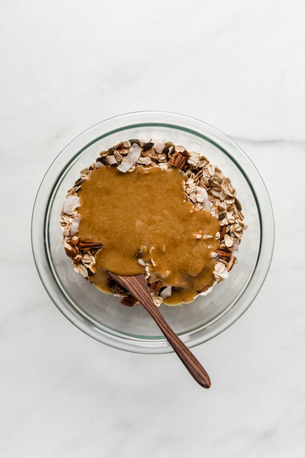 A clear mixing bowl with oats topped with tahini