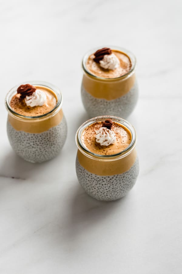 three jars of pumpkin pie chia pudding on a marble board