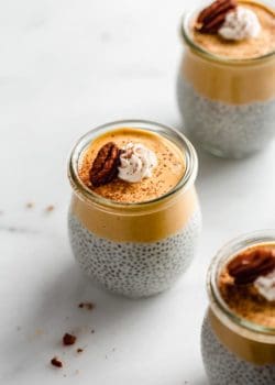 a small jar of pumpkin pie chia pudding topped with whipped cream and a pecan