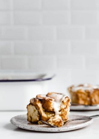 a cinnamon roll on a plate with a white pan in the background