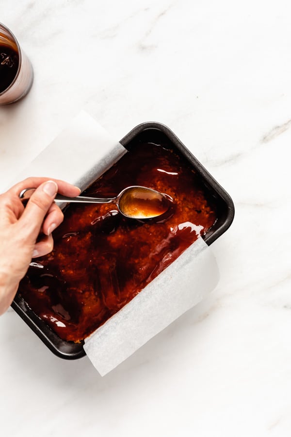 A spoon spreading sauce onto a lentil loaf