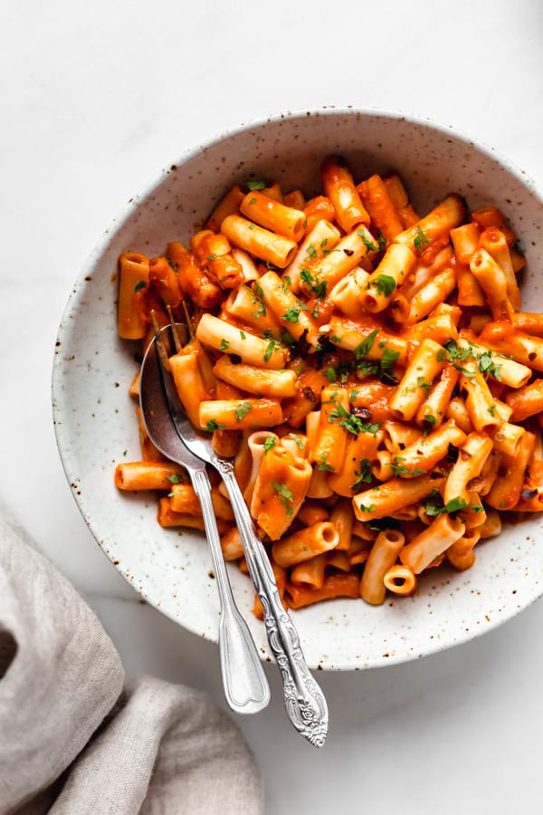 roasted red pepper pasta in a bowl with a fork and spoon in it