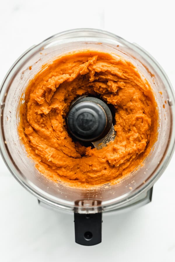 A food processor filled with mashed sweet potato