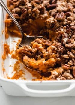 a serving spoon scooping up some vegan sweet potato casserole out of a baking dish