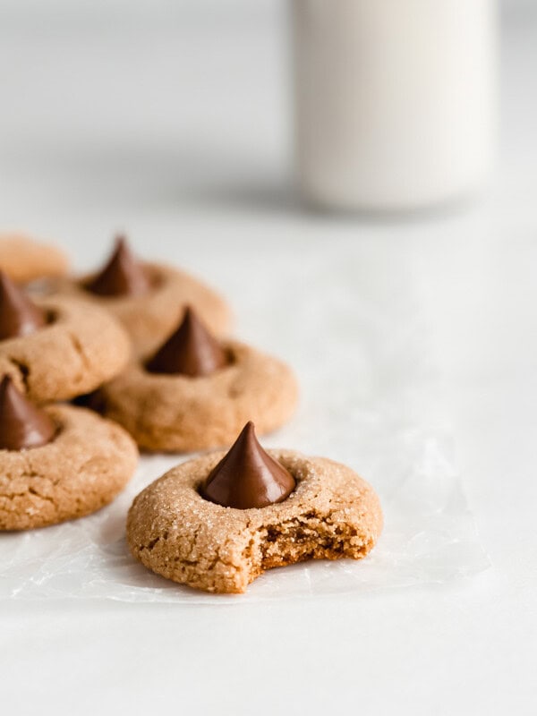 peanut butter blossom cookies on parchment paper with a jug of milk in the back