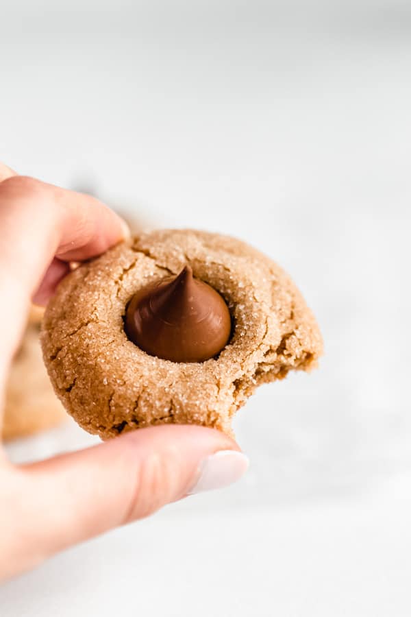 a hand picking up a peanut butter blossom cookie