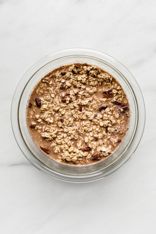 a mixing bowl with oats, almond milk and pecans
