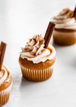 a pumpkin spice latte cupcake topped with sprinkled pumpkin spice and a cinnamon stick
