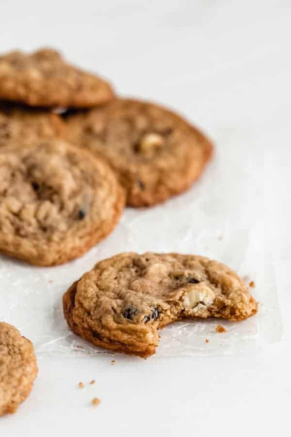 a chewy white chocolate cranberry cookie on some parchment paper with a bite taken out of it