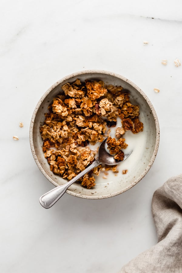 a bowl of banana bread granola with almond milk and a napkin on the side