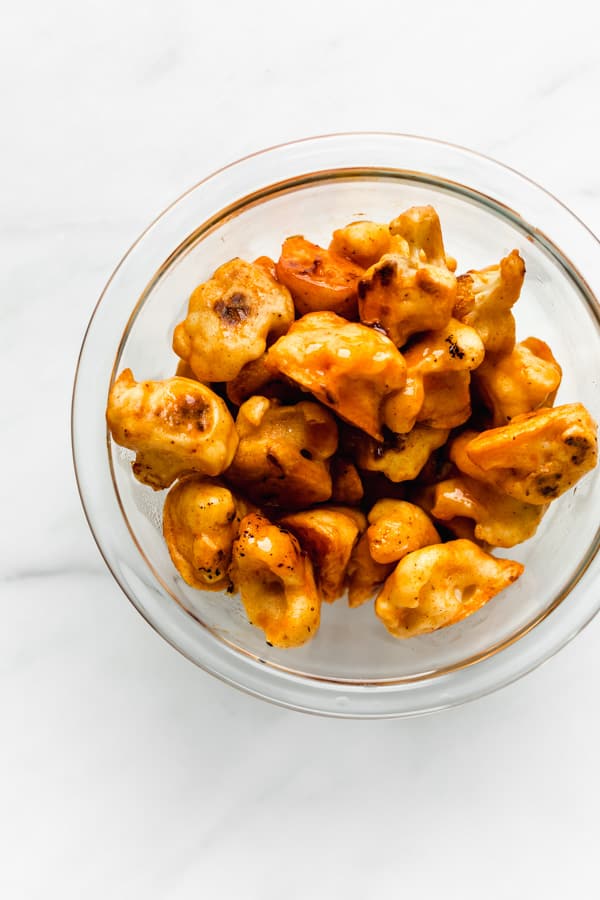 a clear mixing bowl with buffalo cauliflower wings