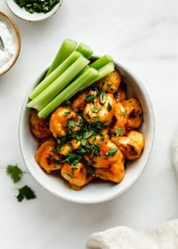 buffalo cauliflower wings in a bowl with celery on the side