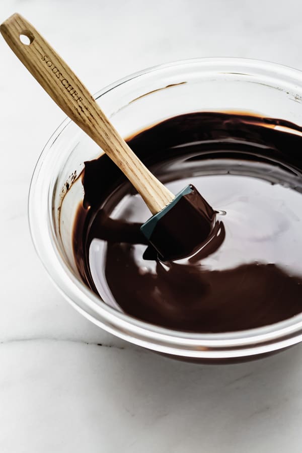 a mixing bowl of dark chocolate with a spatula in it