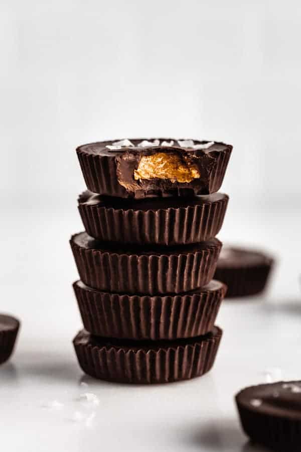 a stack of dark chocolate almond butter cups with the top one missing a bite out of it