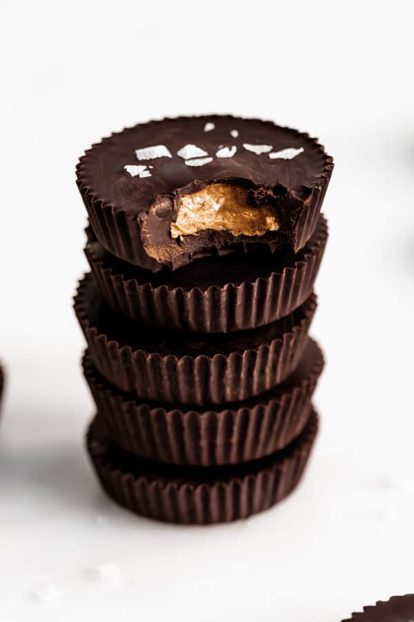 a stack of 5 dark chocolate almond butter cups topped with flaked sea salt