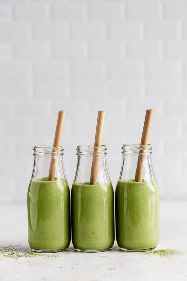 three bottles of matcha green tea smoothies with bamboo straws in them