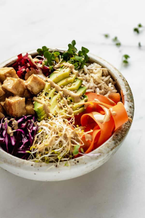 a close up of a buddha bowl with dragon sauce drizzled on top