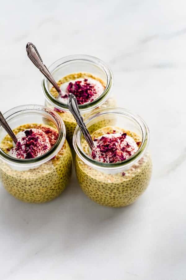 three jars of chia golden milk latte chia pudding topped with yogurt and rose petals
