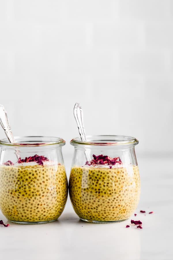 two jars of golden milk chia pudding with spoons in them