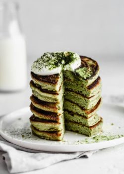 a stack of matcha pancakes with a cut taken out of it