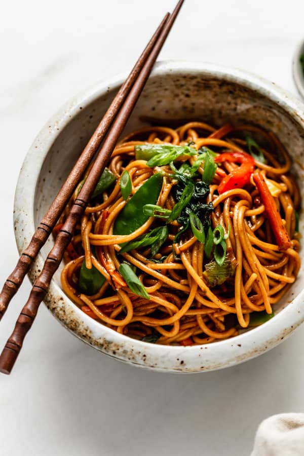vegetable lo mein in a ceramic bowl with chopsticks
