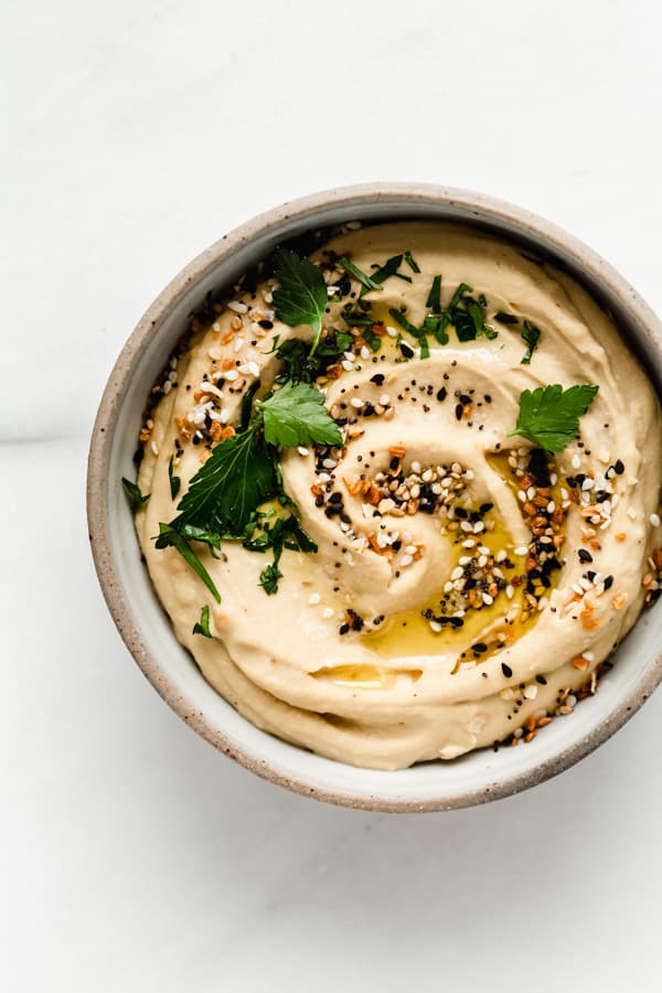 everything bagel hummus in a small white bowl