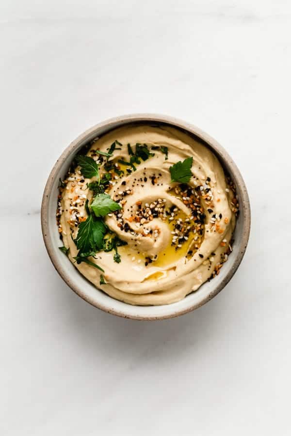 Everything bagel hummus in a small bowl topped with everything bagel spice
