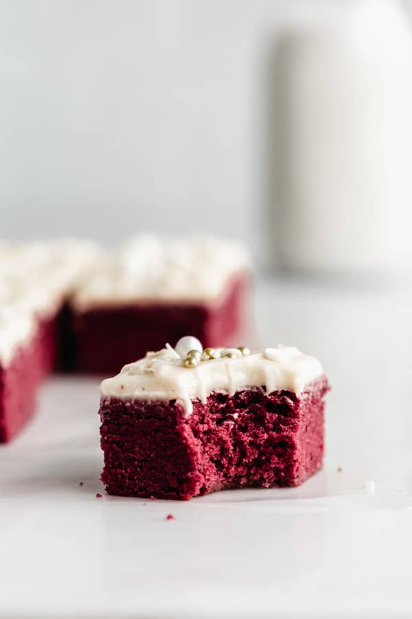 A red velvet brownie with white icing with a bite taken out of it