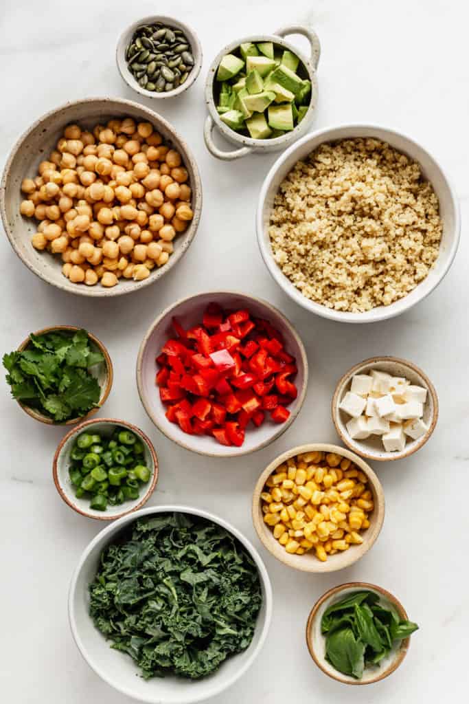 Ingredients for a quinoa power bowl laid out on a marble table