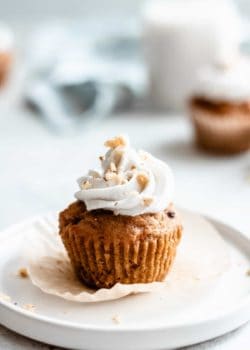 a carrot cupcake topped with coconut whipped cream and crushed walnuts