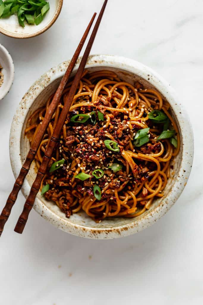 Vegan dan dan noodles topped with green onions and sesame seeds