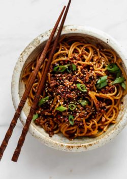 A bowl of vegan dan dan noodles with chopsticks on top
