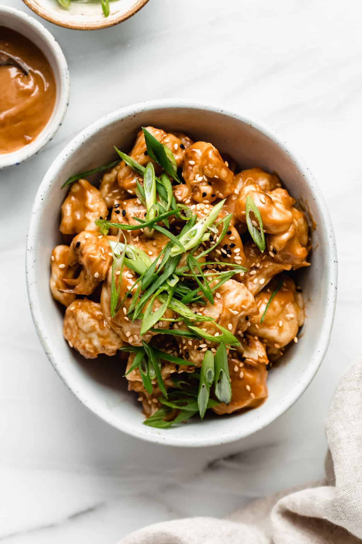A bowl of Thai cauliflower wings topped with green onions and sesame seeds
