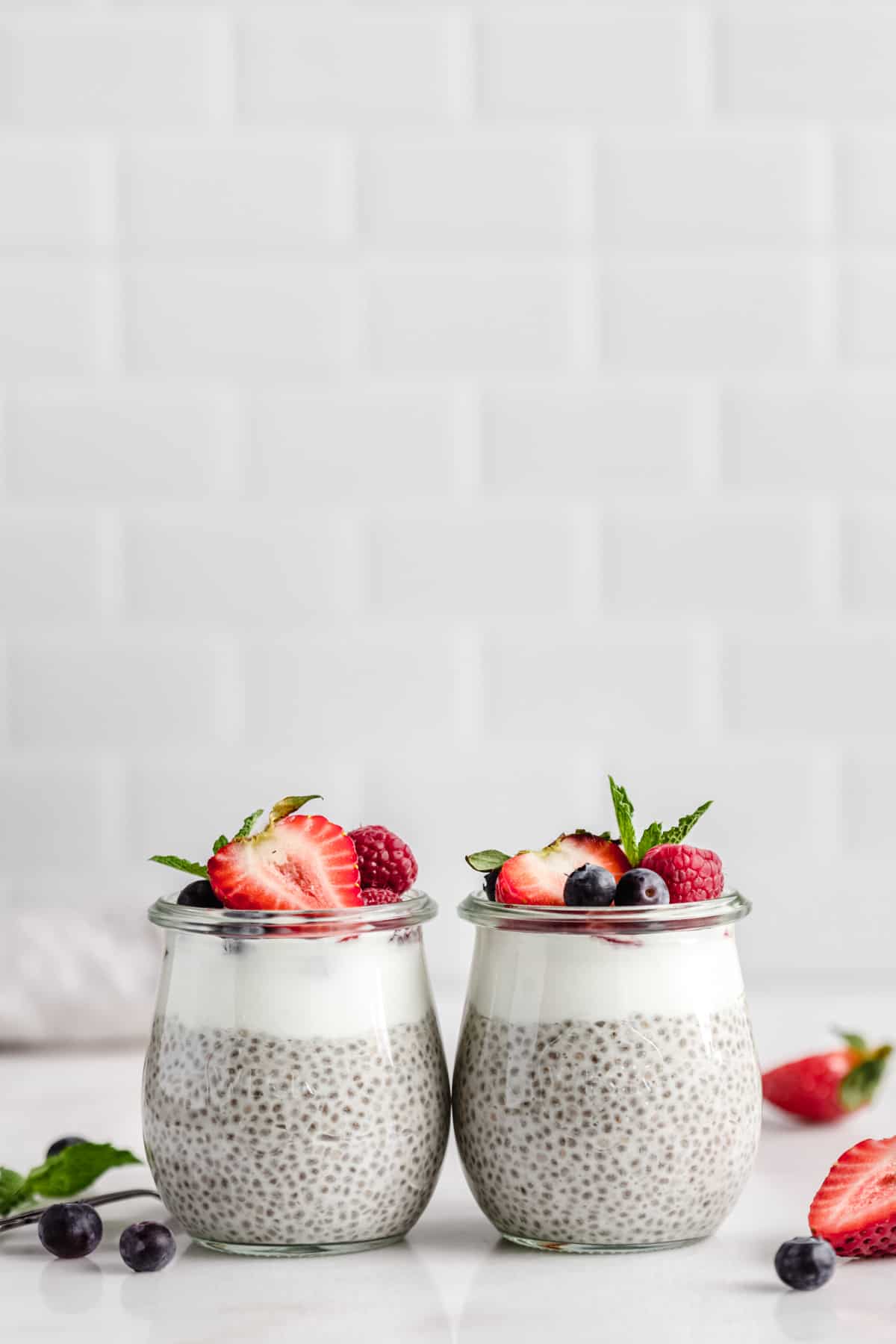 two small cups of vanilla chia pudding next to each other topped with berries