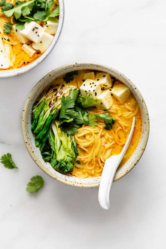 a bowl of vegetarian laksa with a big spoon in it