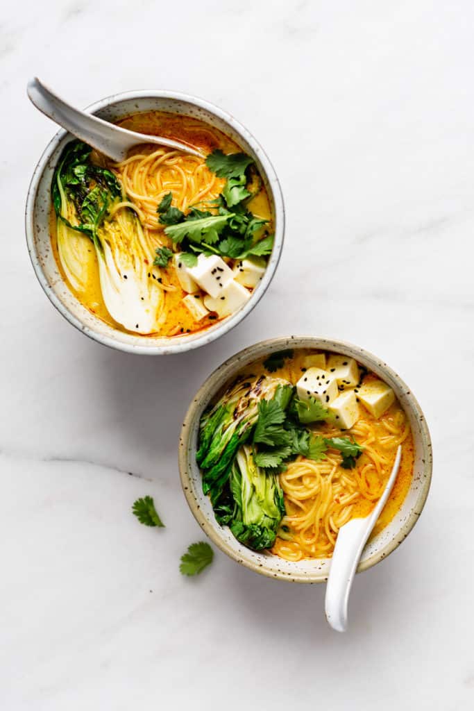two bowls of vegetarian laksa on a marble board