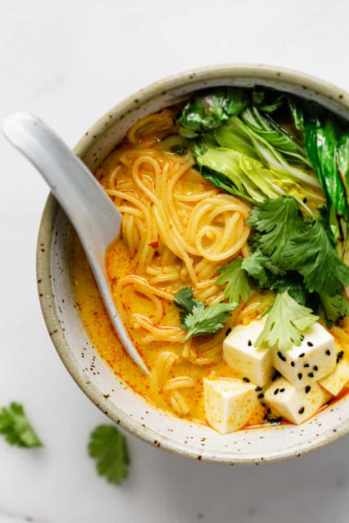 laska soup, noodles, bok choy and tofu in a bowl