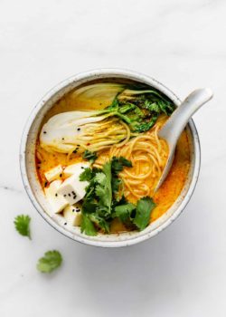 A bowl of vegetarian laksa with bok choy and noodles in it